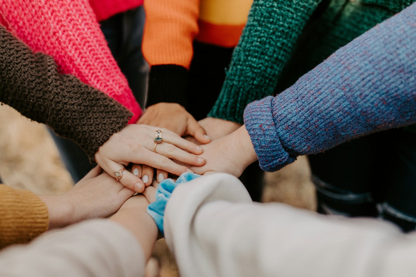 A diverse group of people stacking their hands together in support, representing Hunza's inclusive community.